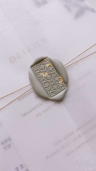 Light gray Talavera tile pattern rectangular wax seal embellished with gold leaf on vellum jacket