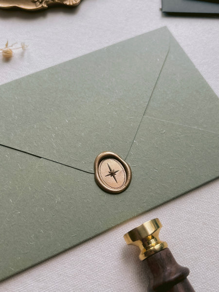 oval star mini gold wax seal on an olive green envelope