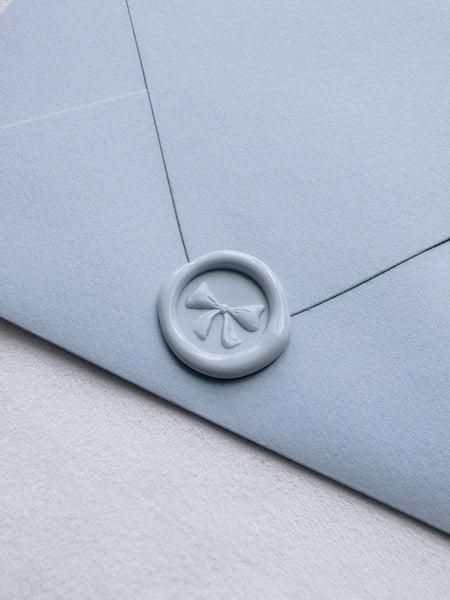 Mini pale blue wax seal featuring a ribbon bow design with 3D engraving details on a sky blue envelope