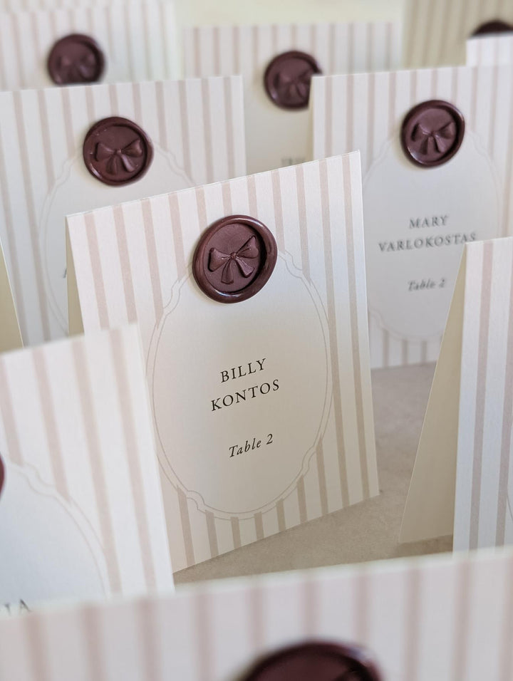 dark purple 3D ribbon bow mini wax seals featured on cream and tan striped wedding place cards 