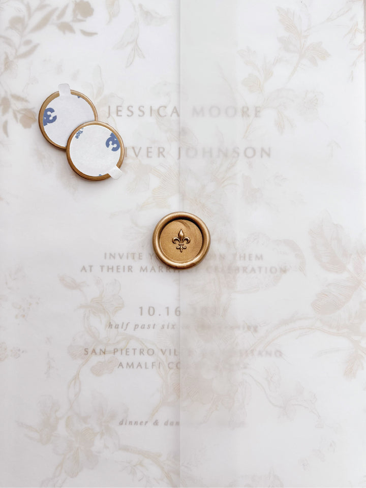 Gold 3D fleur de lis mini wax seal stickers with self-adhesive backings on a beige floral vellum jacket