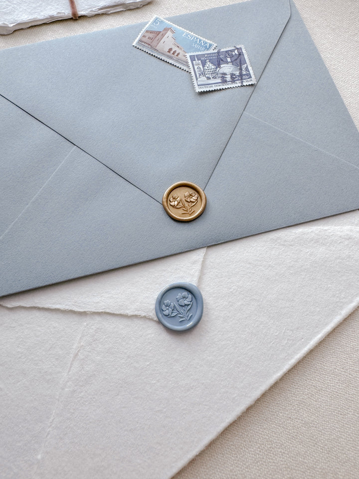light gold and dusty blue 3D mini gardenia floral wax seals on dusty blue and white envelopes 