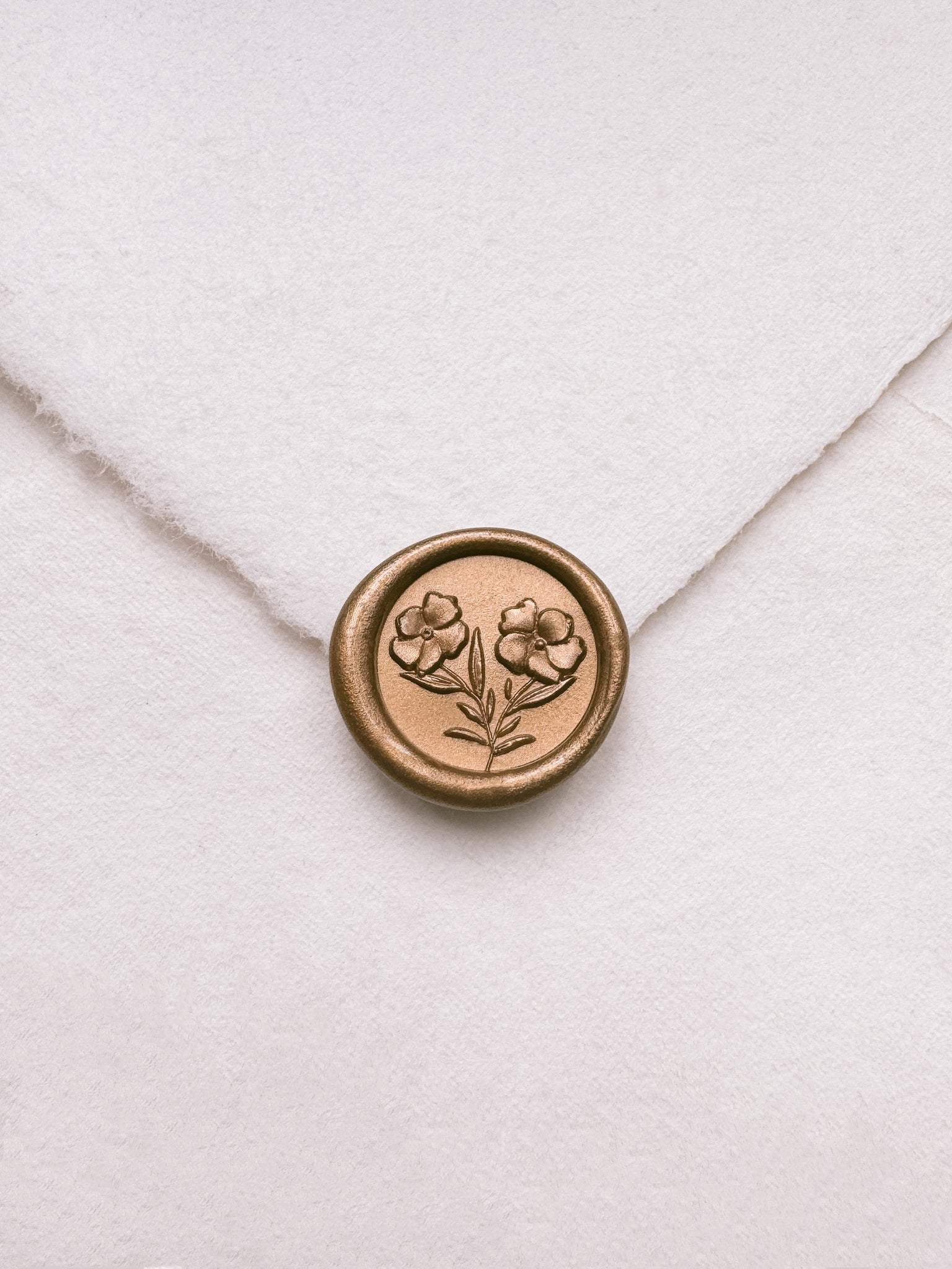 Mini gold wax seal featuring gardenia flowers with 3D engravings on a white handmade paper envelope