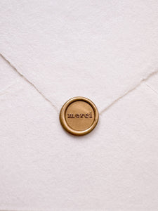 Mini gold thank you wax seal featuring "merci" in a serif font 