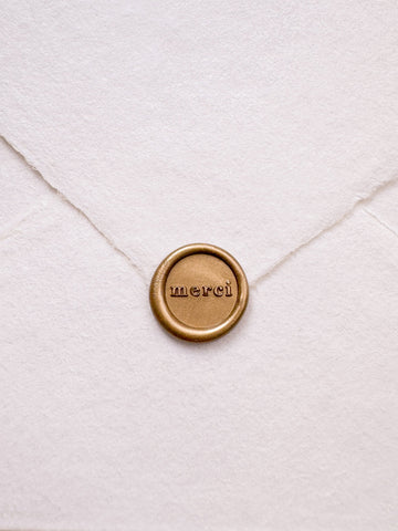 Mini gold thank you wax seal featuring "merci" in a serif font 