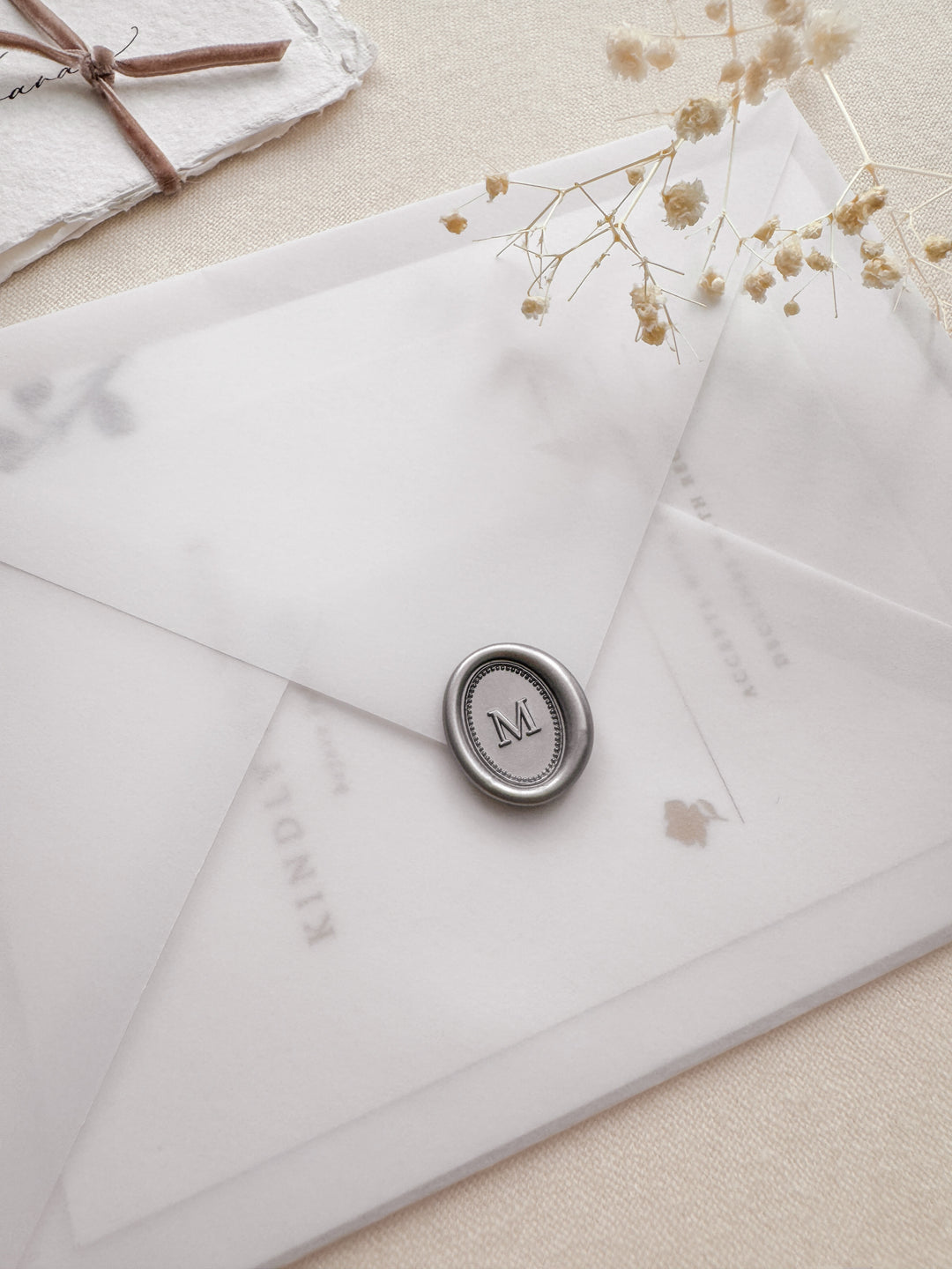 Personalized initial silver mini oval border wax seal featuring a custom monogram on a wedding invitation vellum envelope 