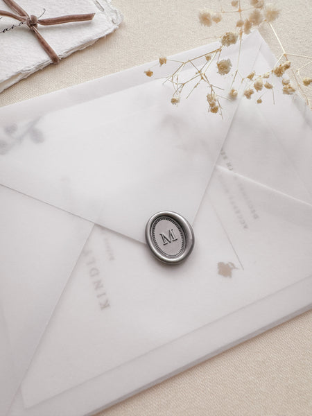 Silver mini oval alphabet wax seal on a vellum wedding invitation envelope