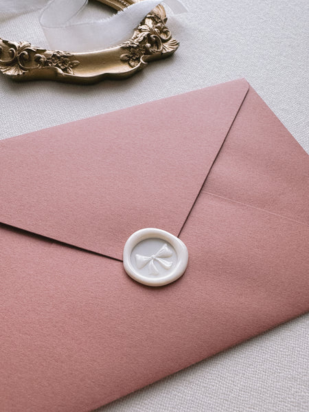 Off-white mini ribbon bow wax seal with 3D engraving details on a red envelope