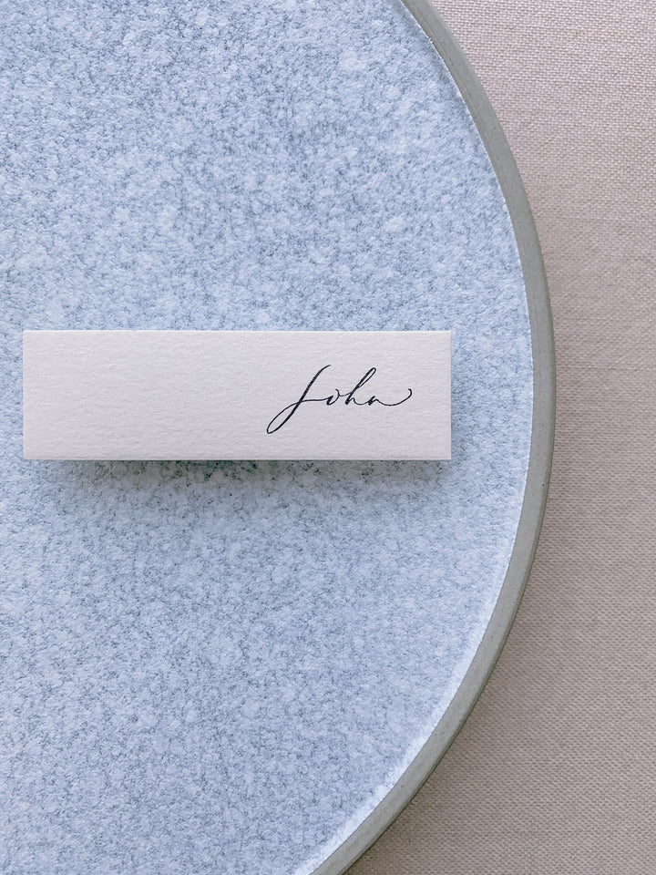 slim place card in beige color hand lettered in modern calligraphy in black ink