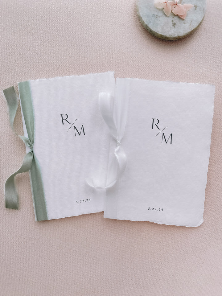 personalized monogram white handmade paper wedding vow books tied in sage green and white silk ribbons