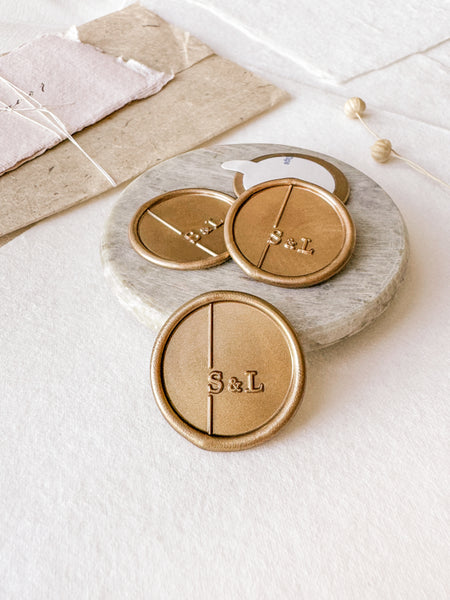 Modern monogram custom wax seals in gold styled with a small gray stone dish, handmade paper and a dried floral branch