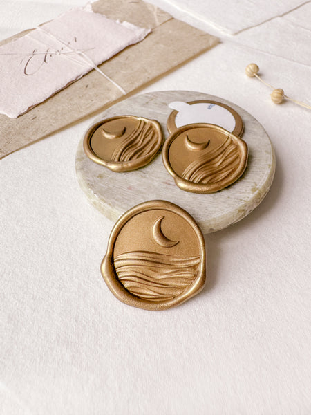 Moon and ocean gold wax seals with 3D engraving styled with a small gray stone dish, handmade paper and a dried floral branch