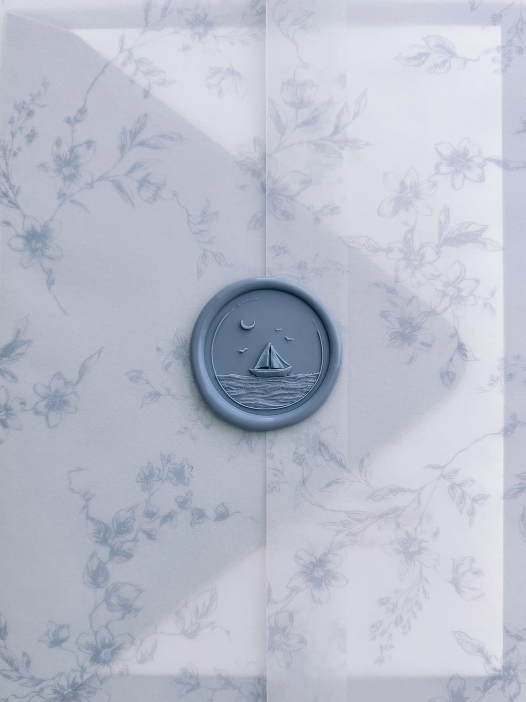 Dusty blue 3D sailboat coastal wax seal on a translucent blue floral print vellum jacket
