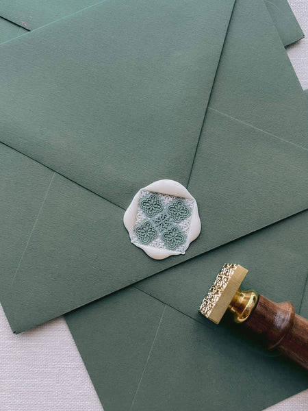 square Moroccan pattern wax seal on olive green envelope