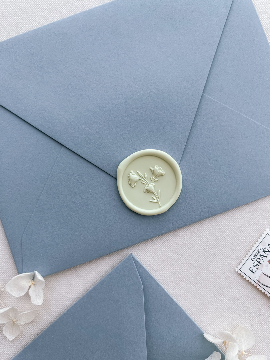 pale green 3D flower design wax seal on a dusty blue envelope