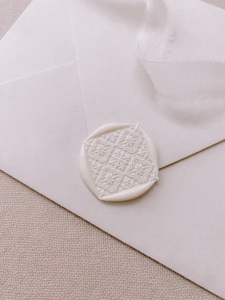 Moroccan tile pattern gold square wax seal in off white on white paper envelope and styled with a strand of white silk ribbon