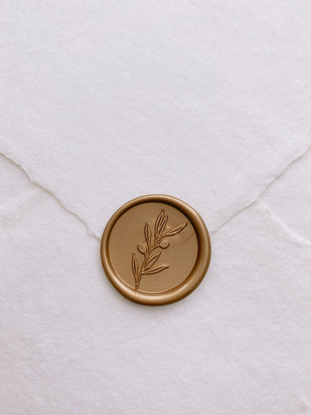 Olive branch wax seal in gold on handmade paper envelope front view