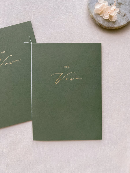 A set of two His and Her gold foil olive green card stock vow books in calligraphy script with fine white twine 