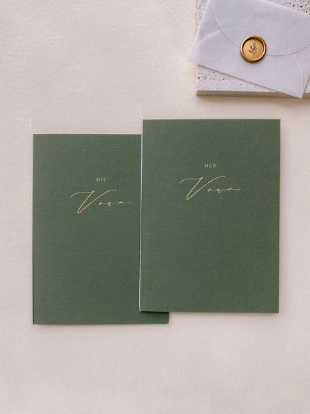 A set of two His and Her gold foil olive green card stock vow books in calligraphy script with fine white twine styled with small vellum envelop with mini leaf wax seal in gold