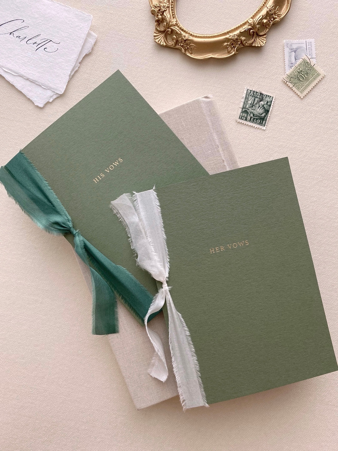 gold foil embossed olive green vow books tied in white and emerald green silk ribbons