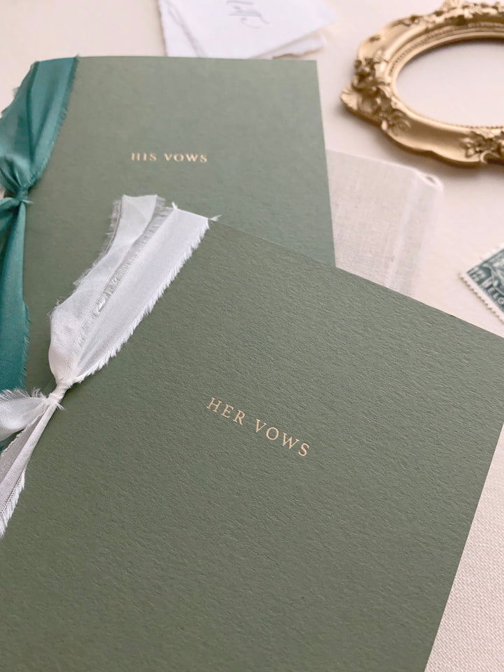 gold foil embossed olive green vow books tied in white and emerald green silk ribbons