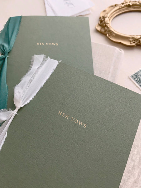 gold foil embossed olive green vow books tied in white and emerald green silk ribbons