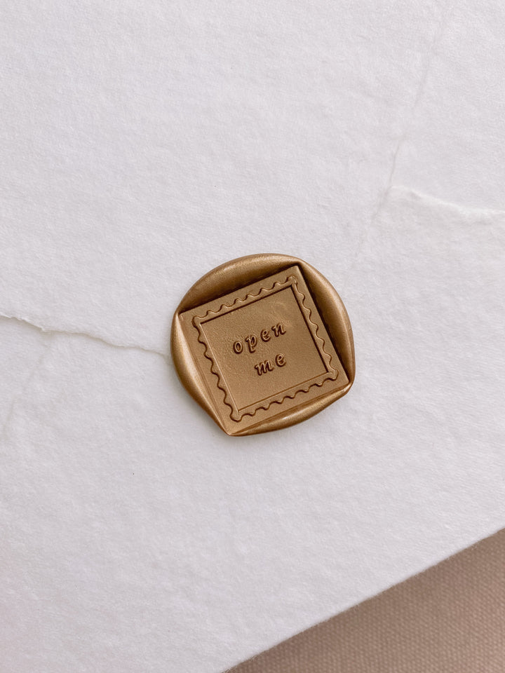 Open me wax seal in gold on beige handmade paper envelope