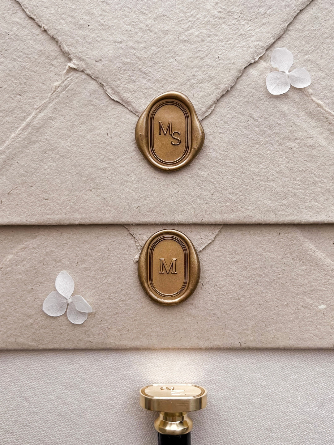 Personalized initials gold oval line border wax seals featuring custom monogram on light brown textured envelopes with a wax stamp head with black handle
