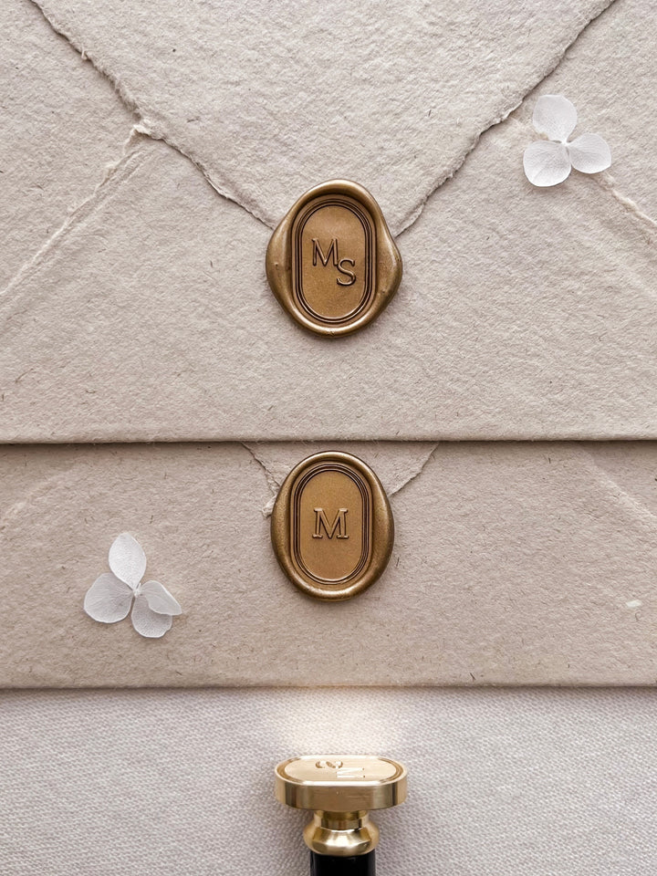 Personalized initials gold oval line border wax seals featuring custom monogram on light brown textured envelopes with a wax stamp head with black handle