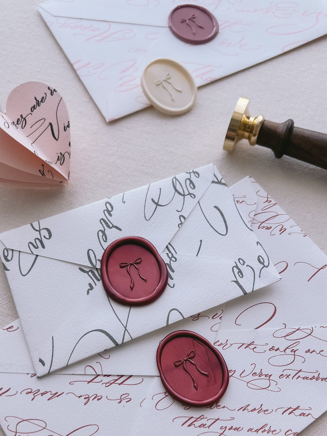 Dark red oval bow design wax seals on white envelopes 