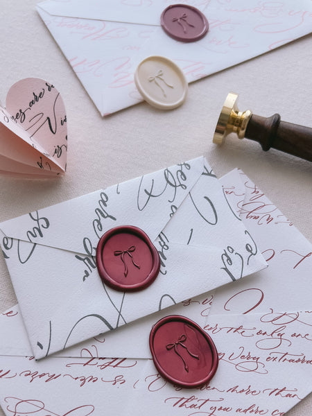 Dark red oval bow design wax seals on white envelopes 