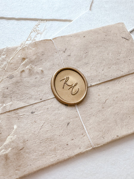 oval calligraphy script monogram gold wax seal on beige textured envelope