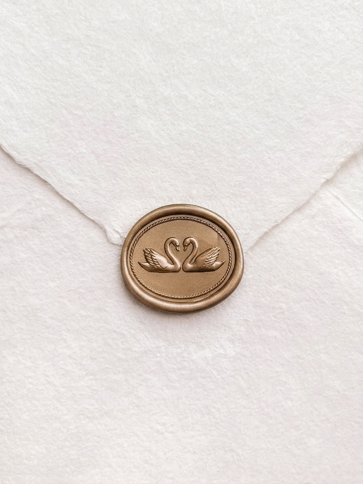 Gold double swans horizontal oval wax seal on a white handmade paper envelope