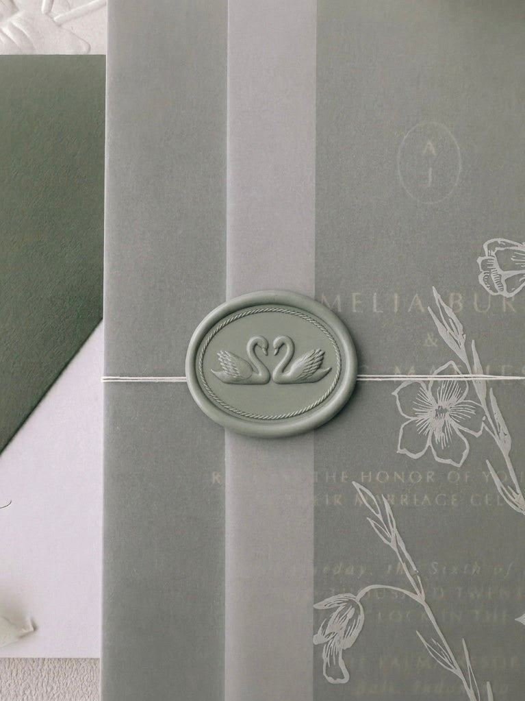 Sage green double swan oval wax seal securing a botanical floral print vellum wrap over an olive green wedding invitation suite.