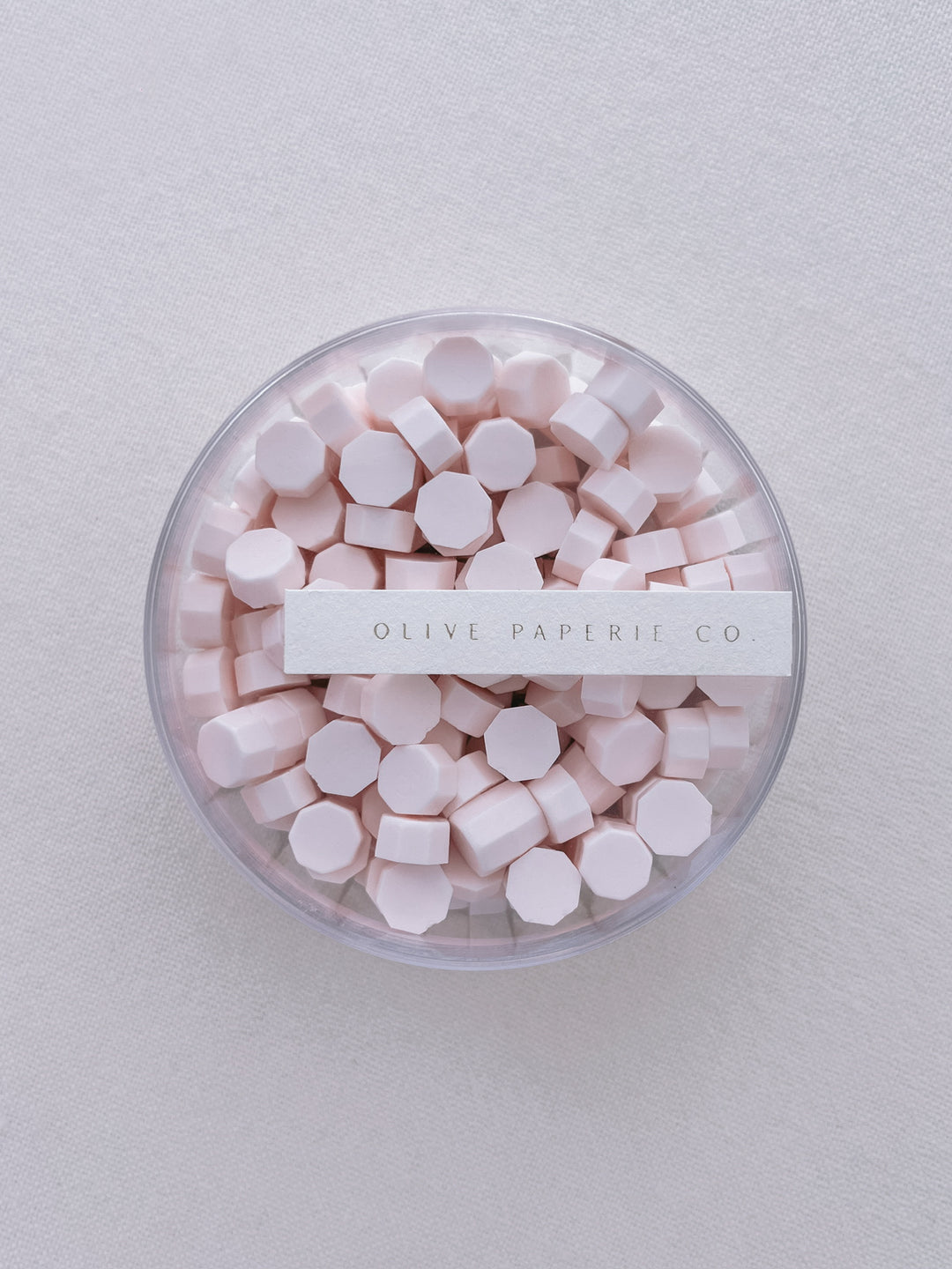 Light pink sealing wax beads in a clear container box