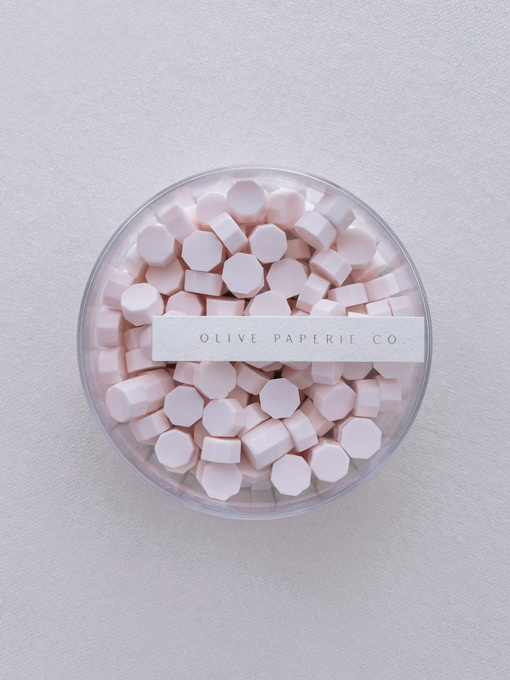 Light pink sealing wax beads in a clear container box