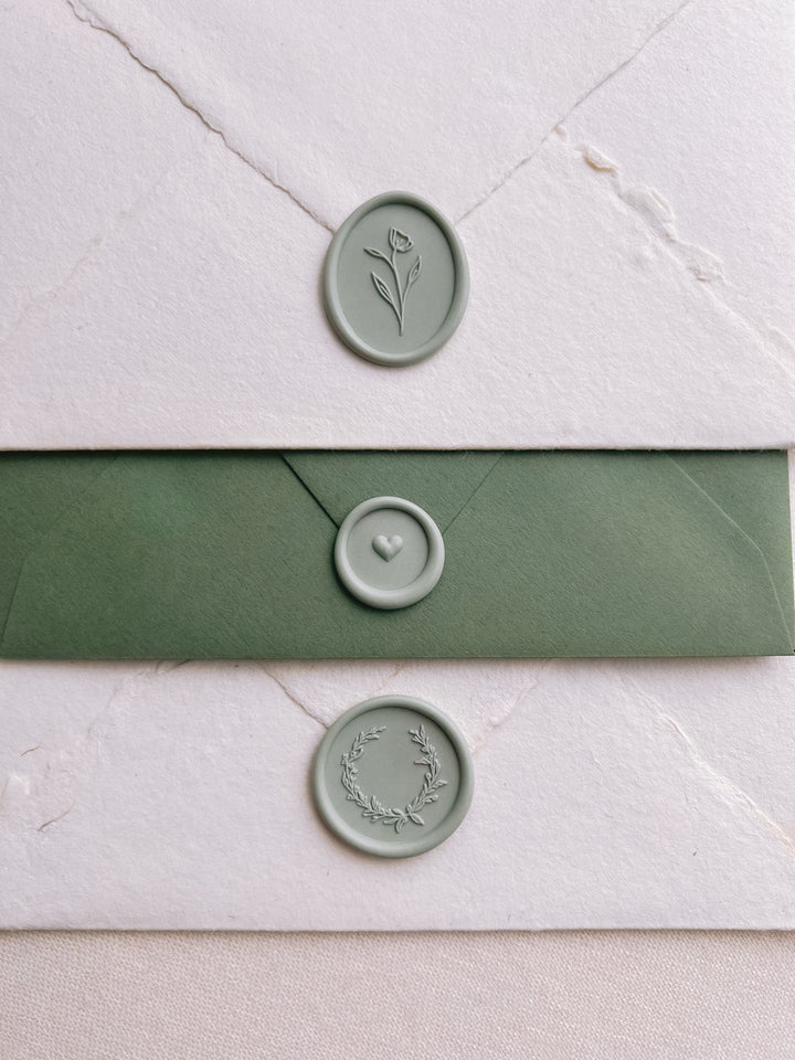 Light sage green colored wax seals featuring a flower design, a mini heart design and a delicate wreath design 