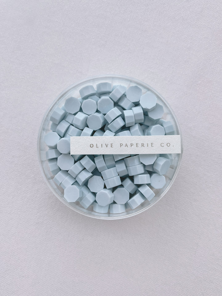 Light blue sealing wax beads in a clear container box