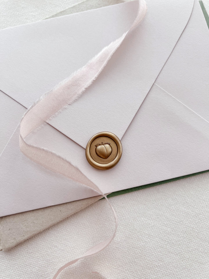 Gold 3D peach emoji mini wax seal on a beige envelope