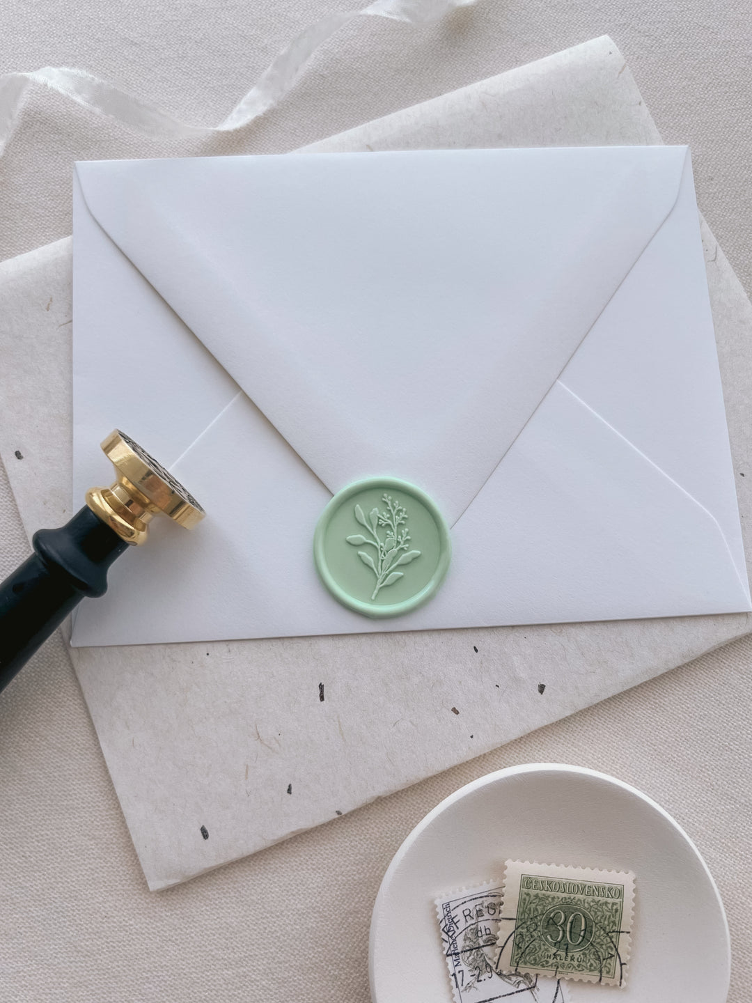 Light green eucalyptus bouquet design wax seal on a white envelope