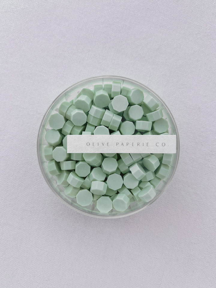 Light green sealing wax beads in a clear container box