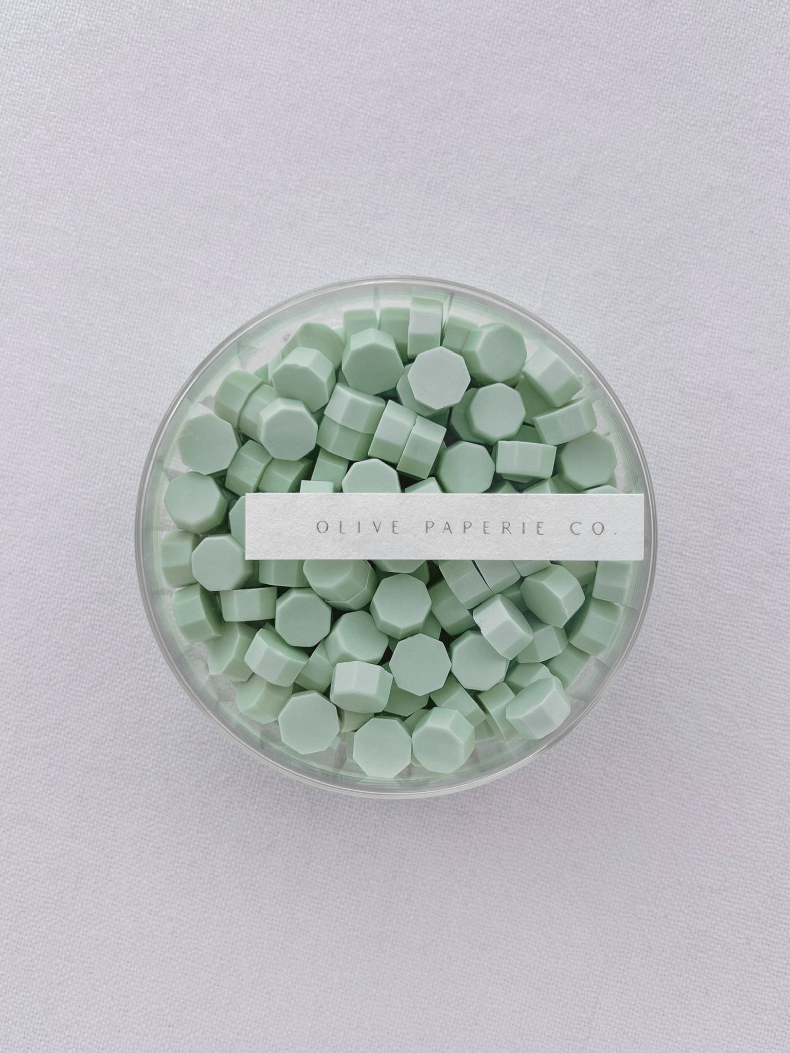 Light green sealing wax beads in a clear container box