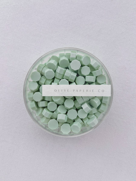 Light green sealing wax beads in a clear container box