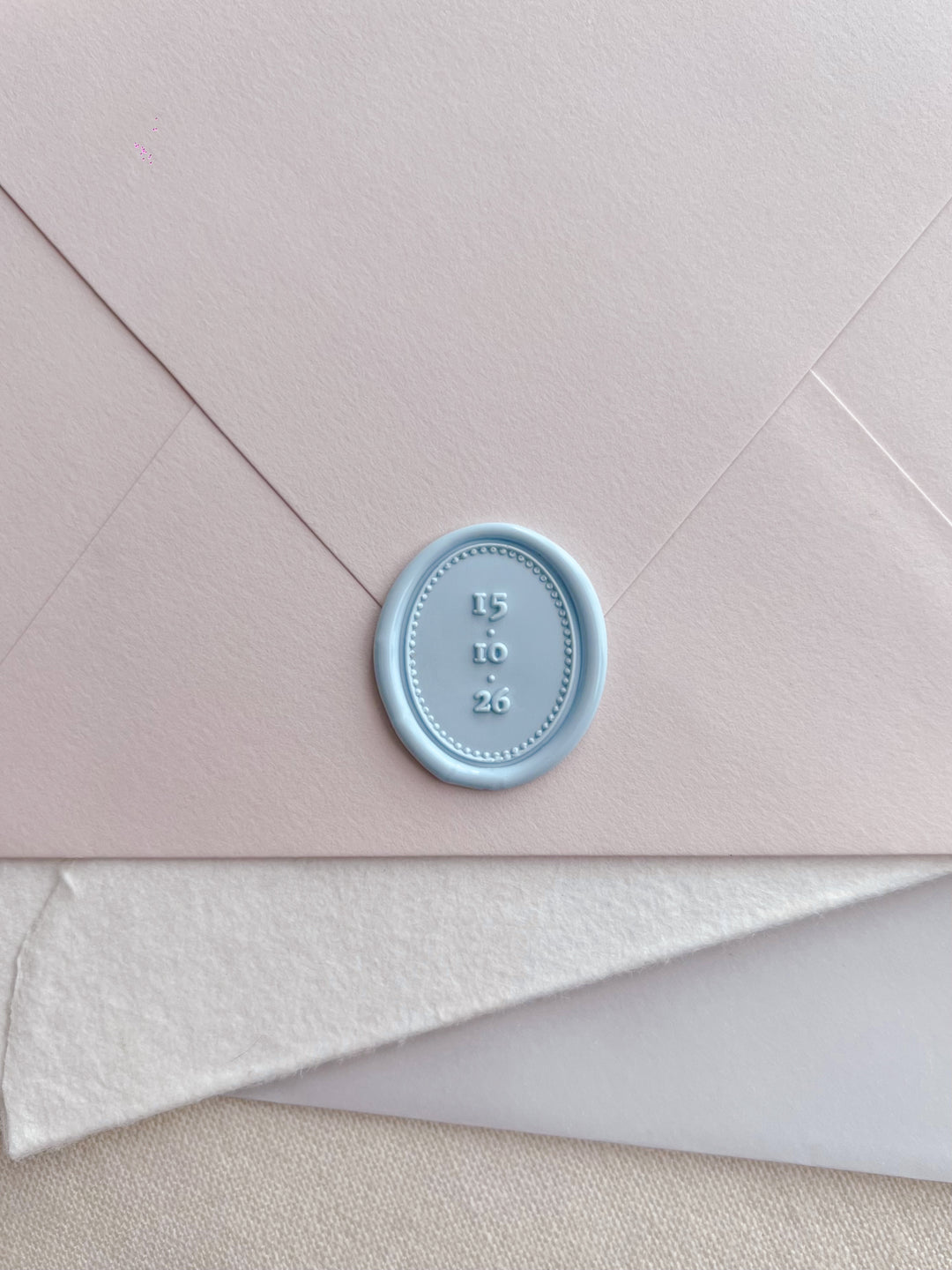 Light blue personalized date oval wax seal on a stack of envelopes 