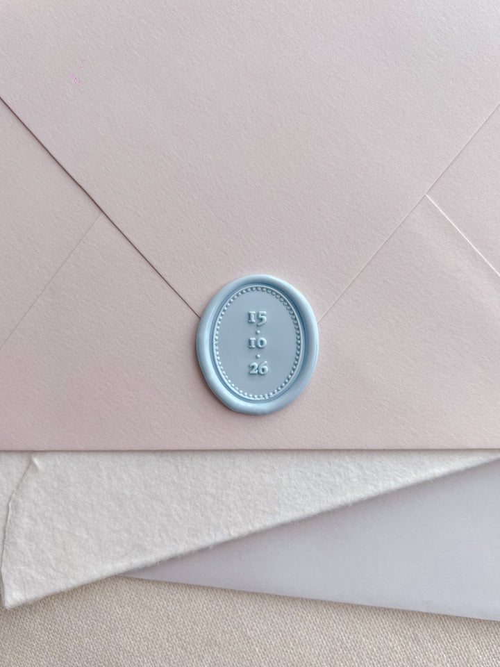 Light blue personalized date oval wax seal on a stack of envelopes 