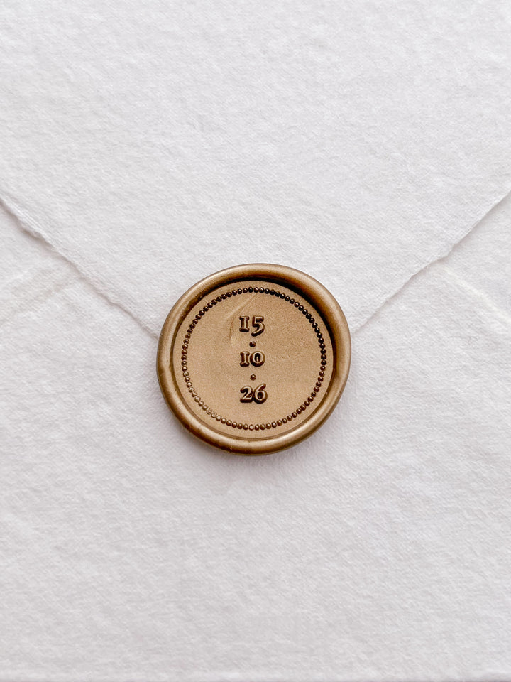 Gold personalized wedding date wax seal on a white deckled edge handmade paper envelope