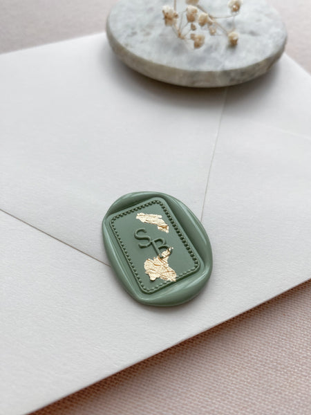 Rectangular border monogram wax seal in sage green embellished with gold leaf on white envelope