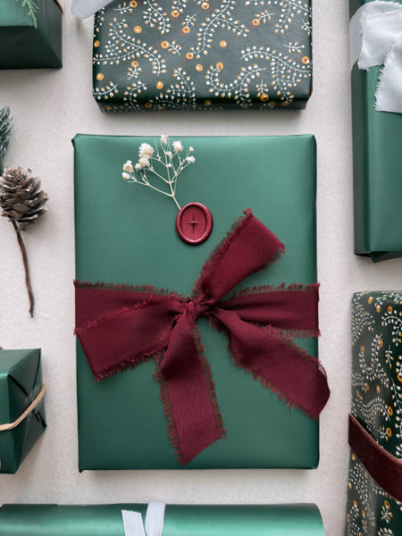 Christmas holiday gift wrap decorated with dark red silk ribbon bow and red Northstar wax seal