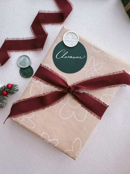 beige Christmas gift wrap decorated with dark red silk ribbon and dark green personalized name tag