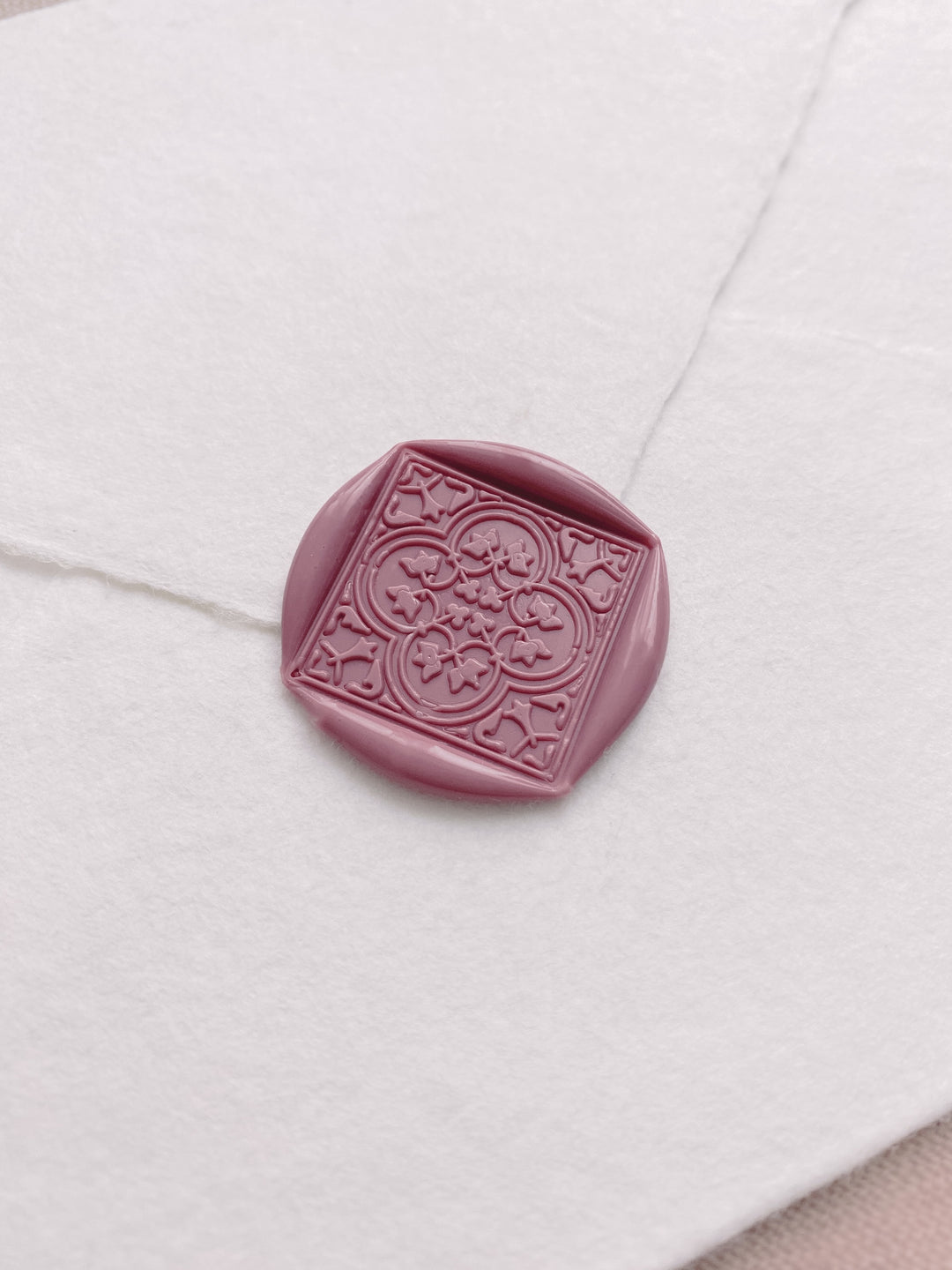 Dusty rose square wax seal featuring quatrefoil Talavera pattern on a white handmade paper envelope